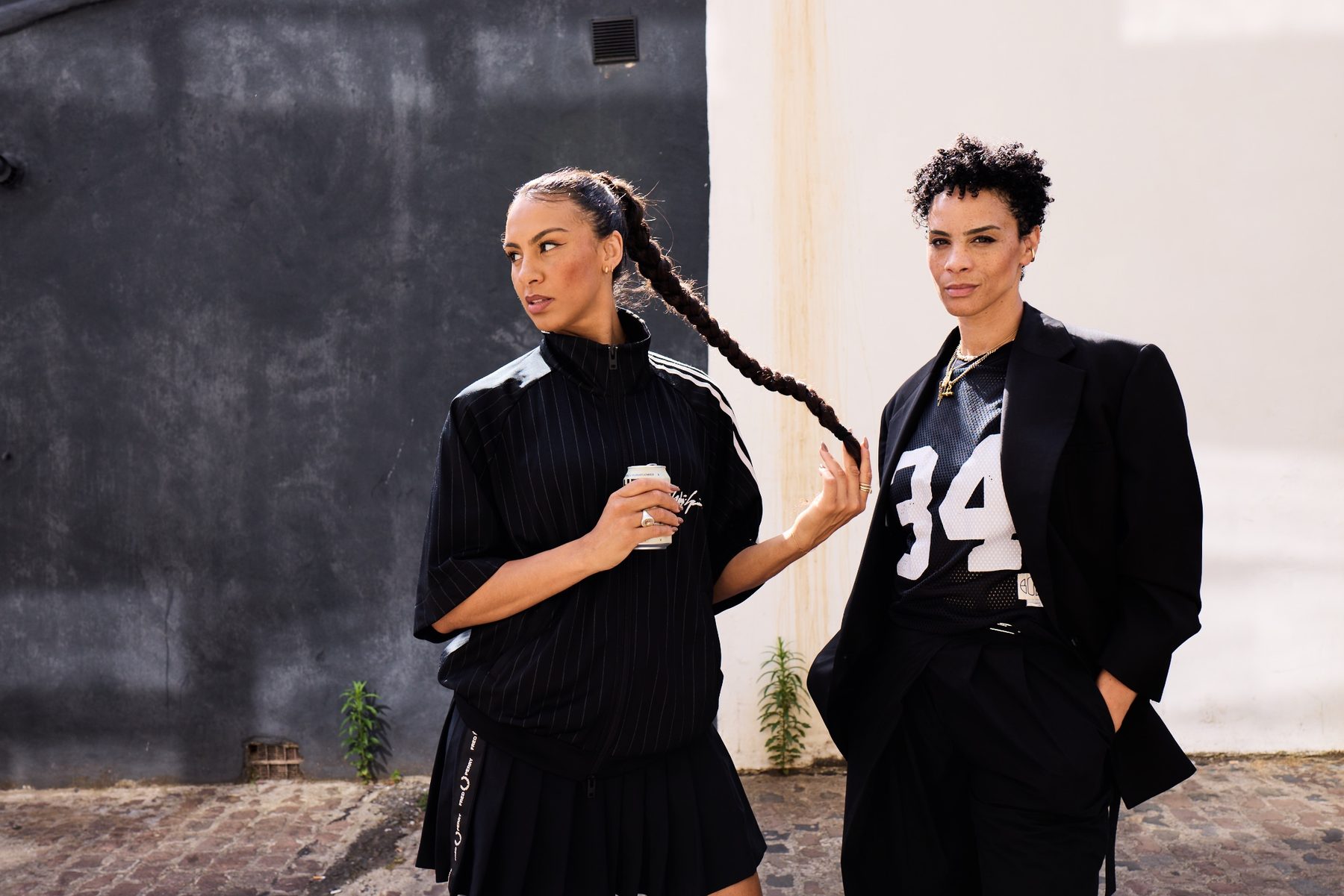 Mel and Holly of House of Molly against a half-black, half-white wall